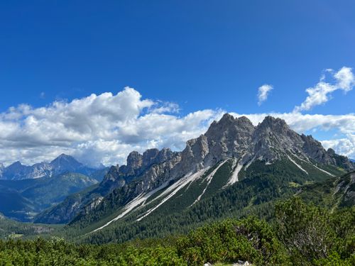 Free Majestic rocky mountain range with lush forest under a clear blue sky. Perfect for nature and travel enthusiasts. Stock Photo