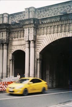 Yellow taxi passing a historic archway in Istanbul, Turkey, capturing urban motion and architectural beauty.