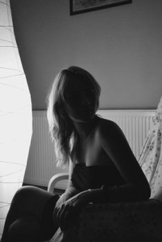 Elegant silhouette of a woman sitting indoors captured in moody black and white.