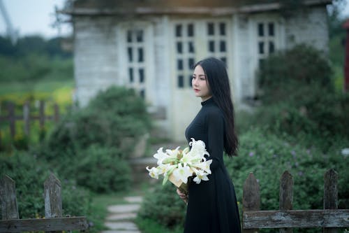 Free A woman in a black dress holding flowers Stock Photo