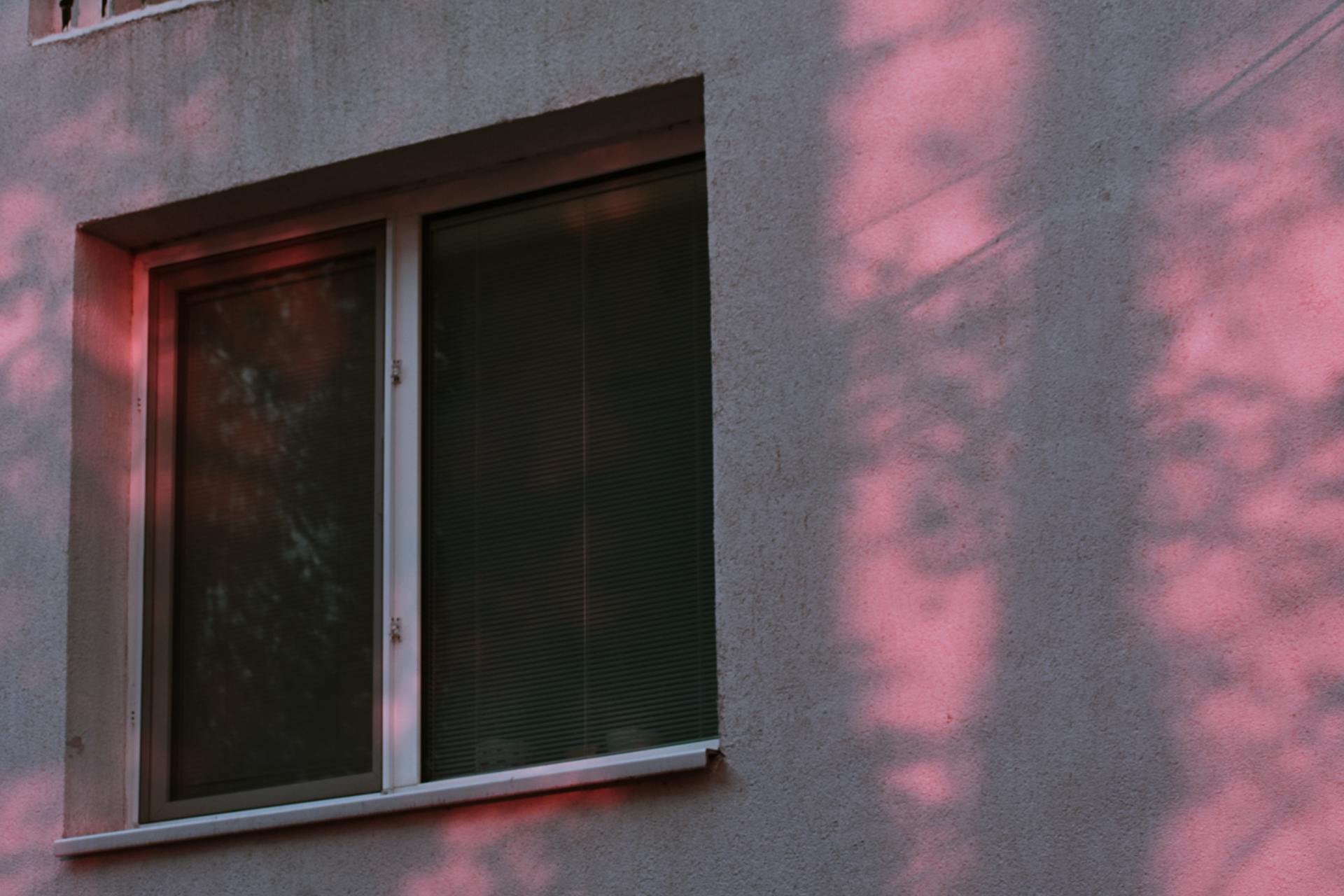 Abstract view of a window with pink light reflections on a concrete wall.