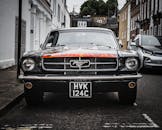 一辆停在伦敦街头的经典福特野马，其前视图展现了标志性的设计