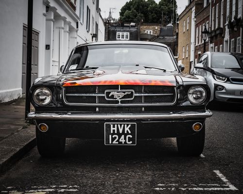 Free Front view of a vintage Ford Mustang parked on a London street, showcasing iconic design. Stock Photo