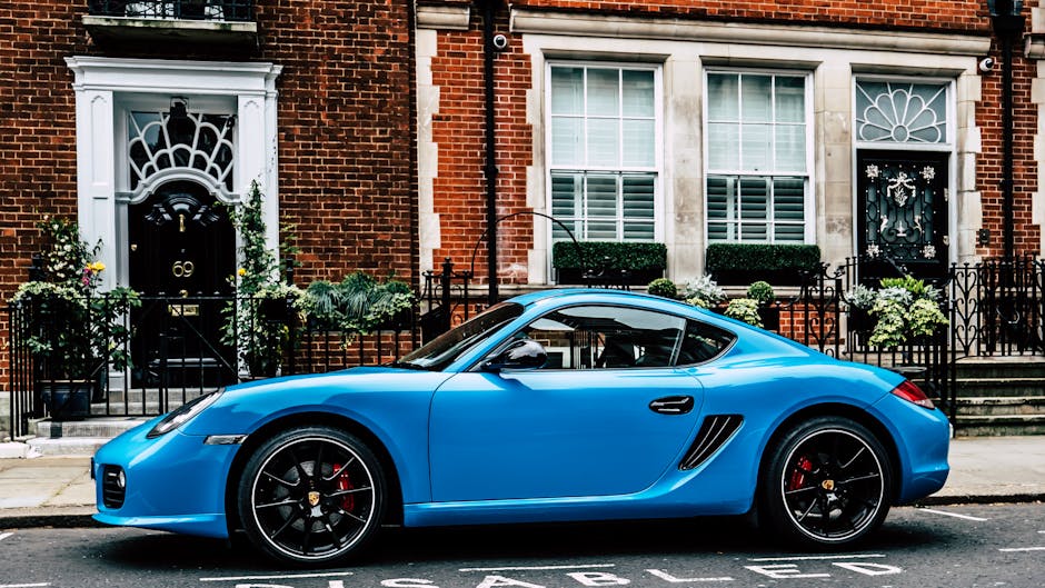 A sleek blue sports car parked in front of classic brick buildings in London.