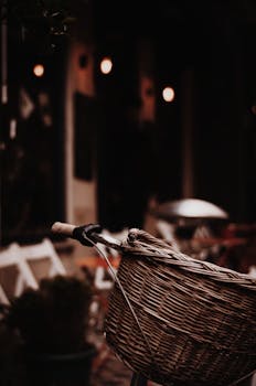 在光线昏暗的街道上，一辆带有柳条篮的自行车特写，唤起了复古的城市氛围