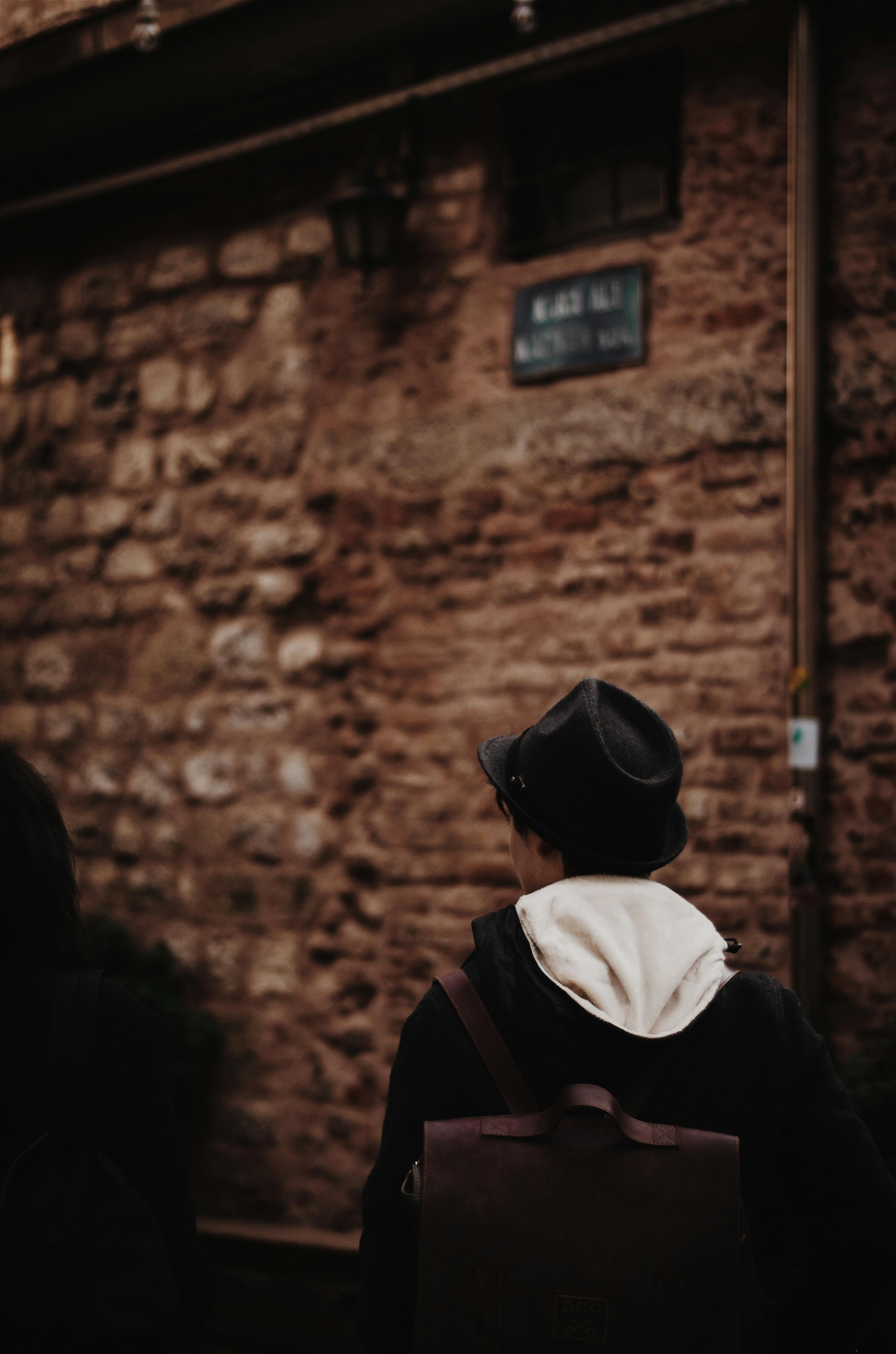 一个戴着软毡帽的人探索了乡村城市的小巷，增添了神秘感和阴谋气息