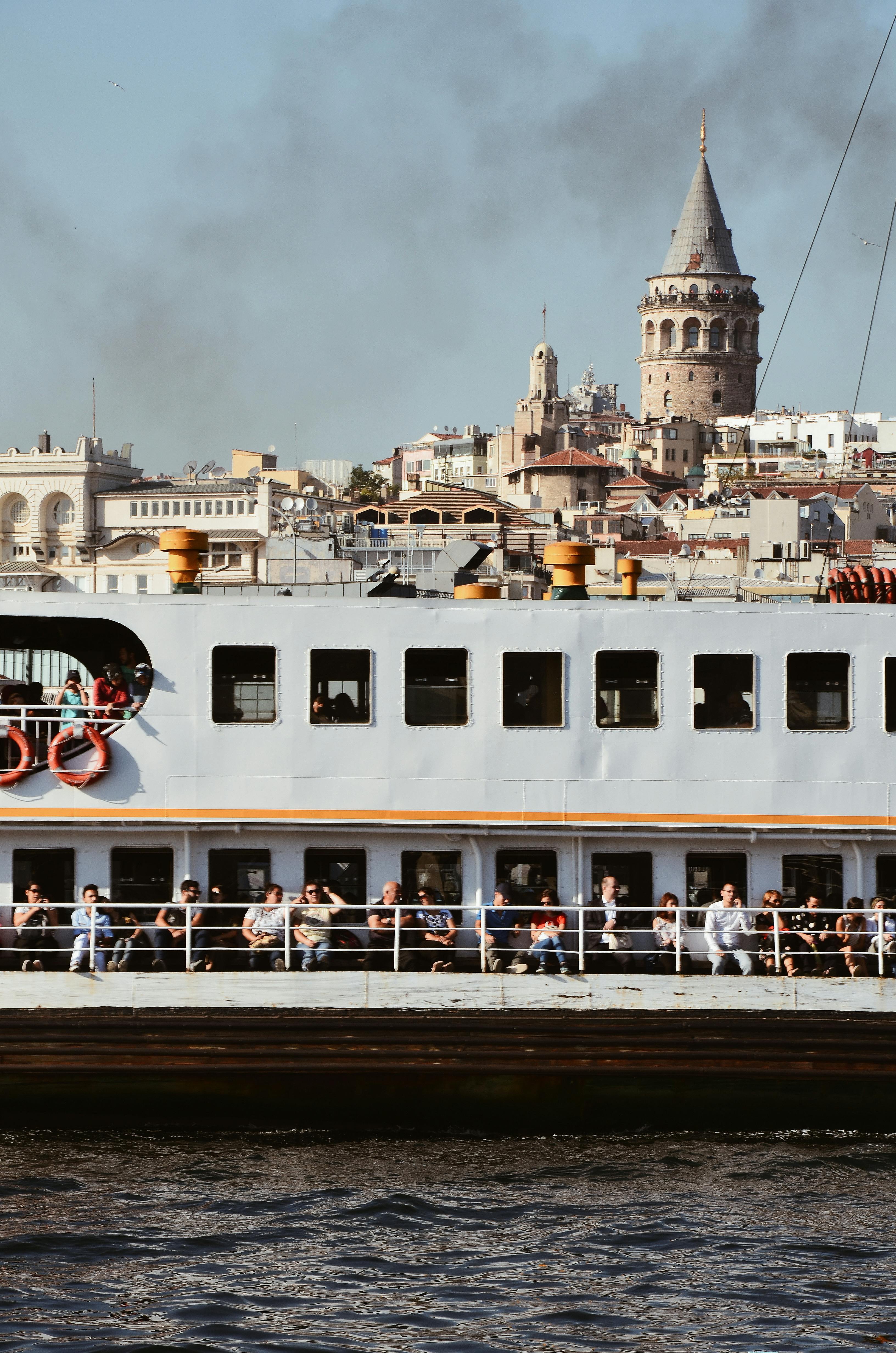 一艘繁忙的渡轮行驶在伊斯坦布尔的水道上，背景是标志性的加拉塔塔
