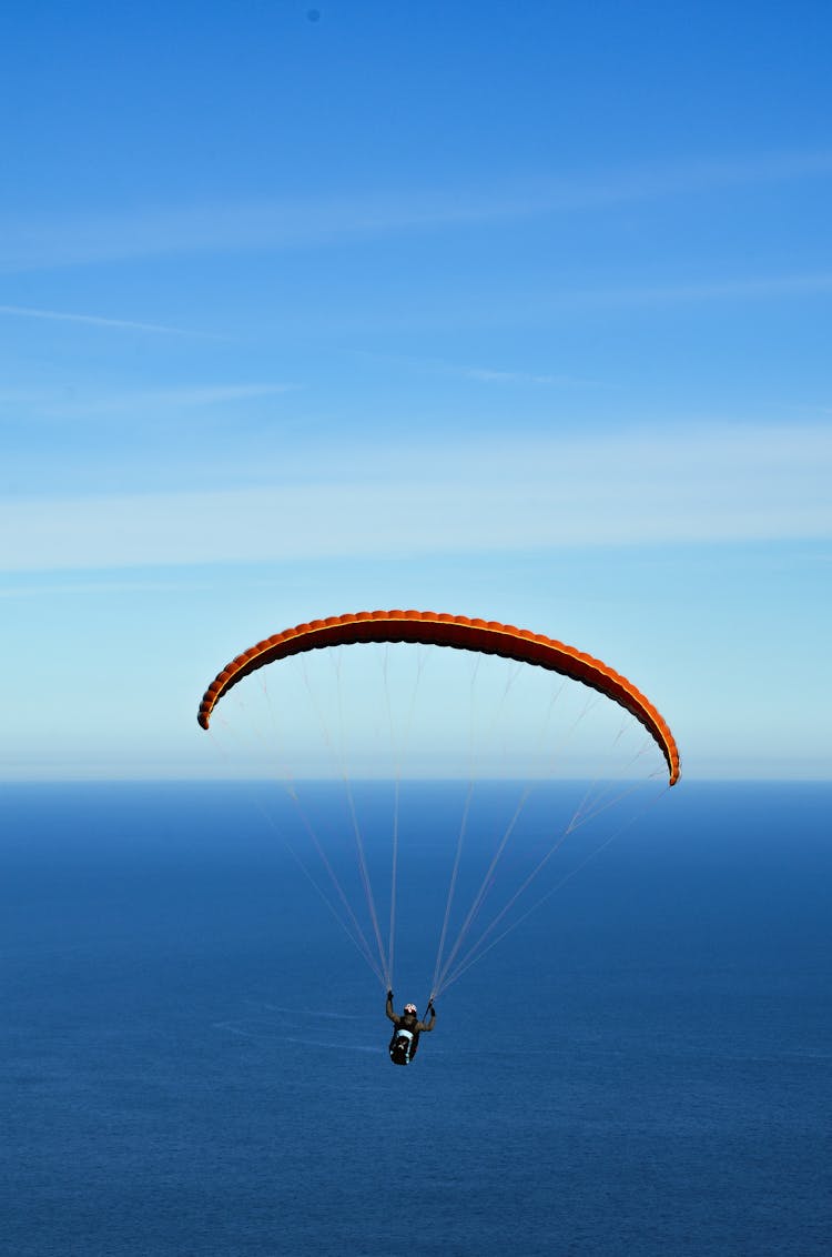 Man On Parachute Over Blue Sea