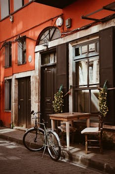 在充满活力的建筑立面旁，风景如画的街景中，停着一辆自行车，坐落着一家迷人的咖啡馆