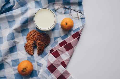 Two Oranges, Two Cookies and a Cup of Milk on Table