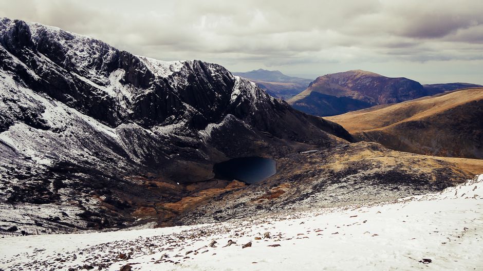 Scenic winter view of snow-capped mountains and valleys in Snowdonia, Wales.