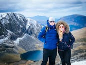 一对夫妇在威尔士斯诺登尼亚的雪山前摆姿势，身后是令人惊叹的冬日景色