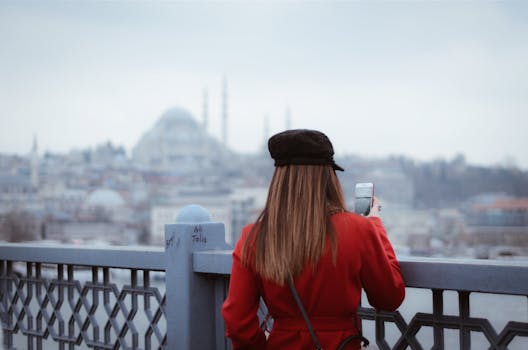 日落时分，一名身穿红色外套的游客拍下了伊斯坦布尔的天际线，照片中有一座清真寺