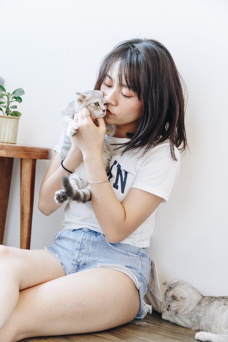 Woman In A White Shirt Kissing A Cat