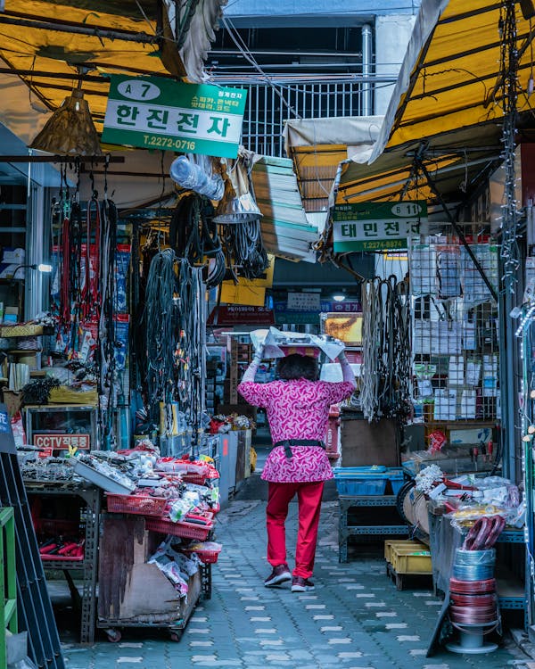 Woman Walking on Pathway Between Stores