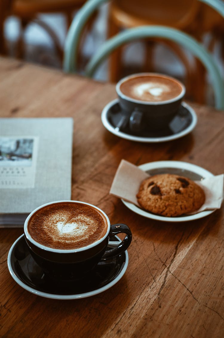 Black Teacup On Saucer Beside Cookie