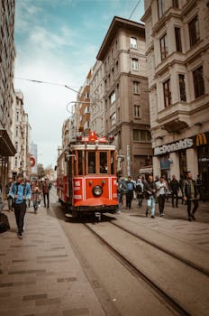 伊斯坦布尔热闹的街道上，一辆历史悠久的红色电车穿行在多样化的行人之中