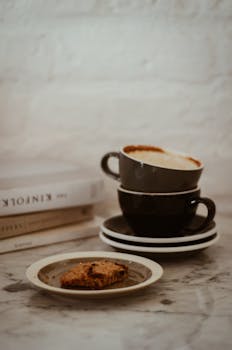 大理石桌子上堆放的咖啡杯和饼干，在室内营造出舒适的静物场景