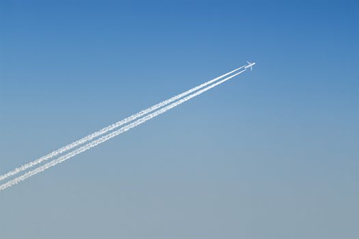 一架飞机在晴朗的蓝天上划出轨迹，展现了航空技术