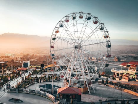 在城市游乐园的摩天轮上，可以欣赏到以日落为背景的优美城市景观