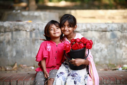 Girls Sitting with Bucket of Flowers