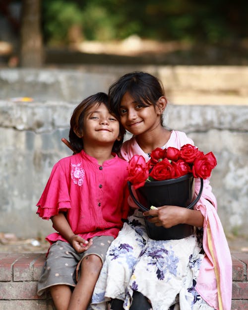 Smiling Girls are Sitting with Bucket of Flowers