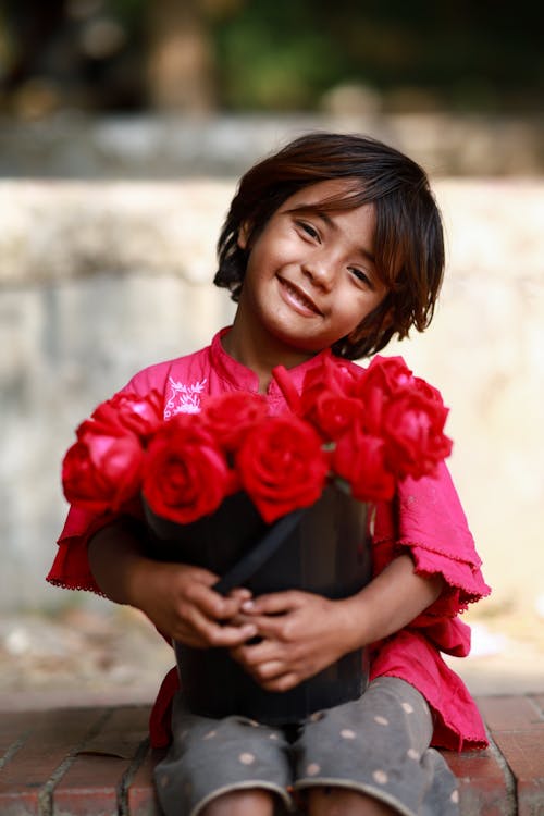 A little girl holding a bunch of red roses
