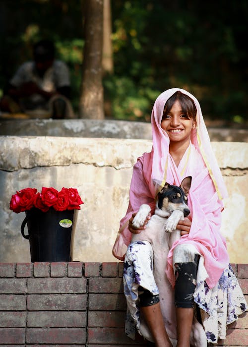A young girl in pink holding a dog