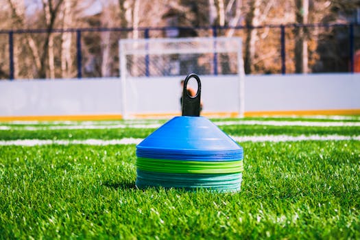 Colorful training cones on an outdoor soccer field with goal in the background.