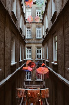 Narrow urban alley decorated with vibrant umbrellas and hanging decor, creating a unique architectural scene.