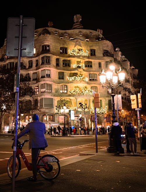 A man riding a bike in front of a building with lights