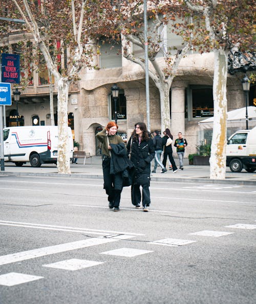 Free Two women walking down a street with a crosswalk Stock Photo