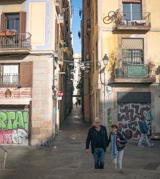Elderly couple walking through a charming alley in Barcelona, showcasing urban life and vibrant architecture.