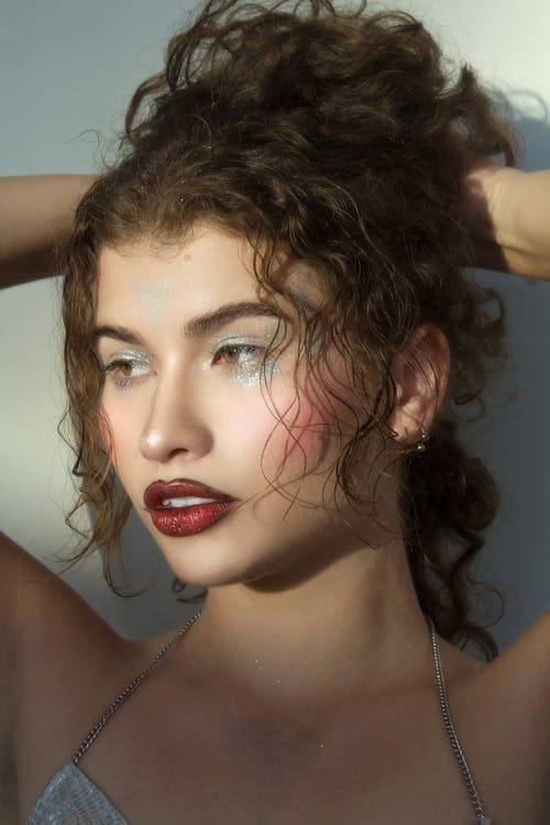 Young Woman with Glitter Eye Shadow Holding Her Wavy Hair Up