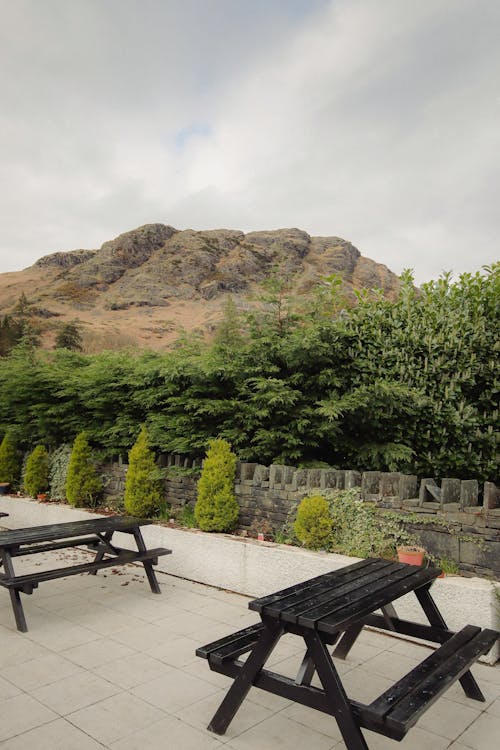 A picnic table with two benches in front of a mountain