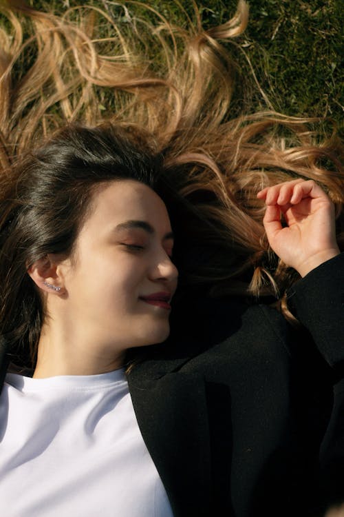 Free A Woman Lying on the Grass in Sunlight and Smiling  Stock Photo