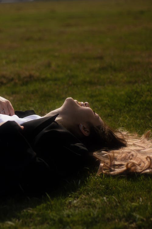 Free A woman laying on the grass with her head in her hands Stock Photo