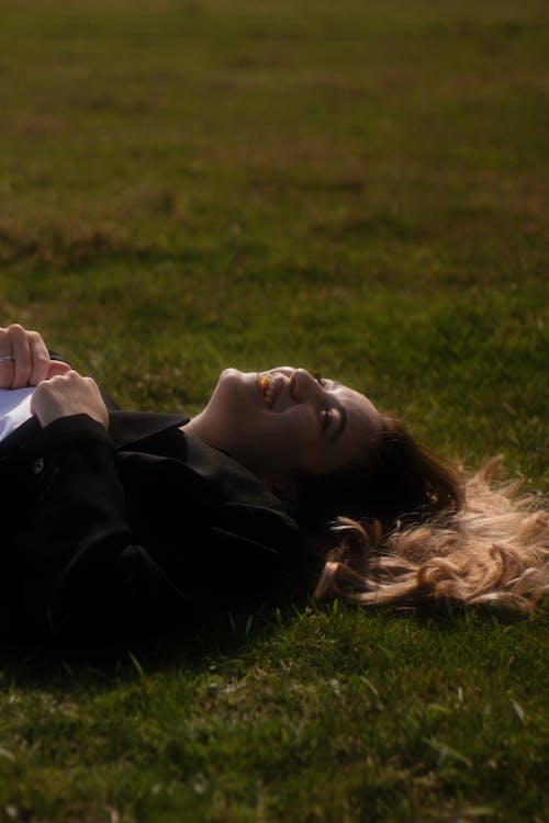 Free A woman laying on the grass with her head in her hands Stock Photo