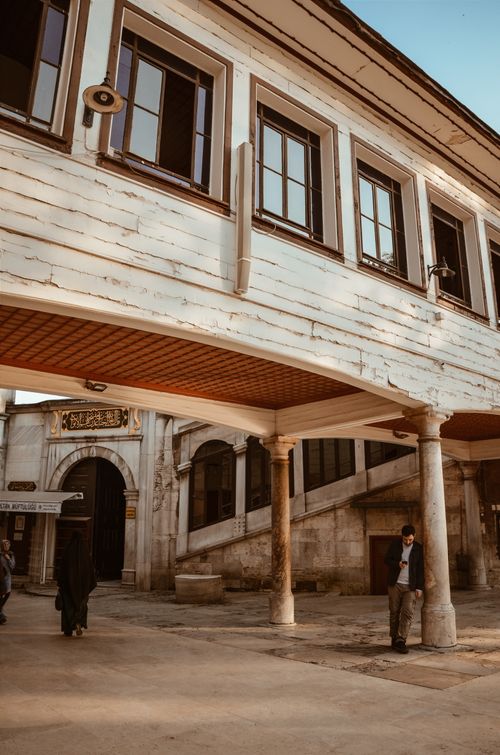Free Exterior architectural view of a historic building with columns and arched entrance, featuring a person walking nearby. Stock Photo
