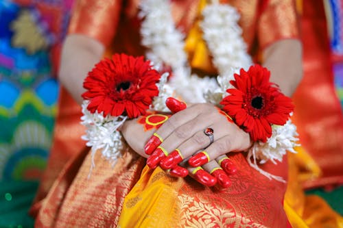 A woman in traditional attire with red flowers on her hands
