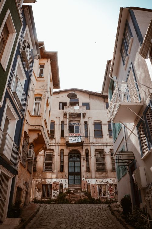 Free Explore a narrow cobblestone street lined with historic buildings and colorful facades on a sunny day. Stock Photo