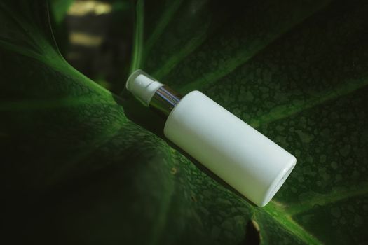 Close-up of a white spray bottle on a textured green leaf, highlighting eco-friendly packaging.