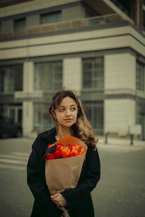 A woman holding a bouquet of flowers in the street