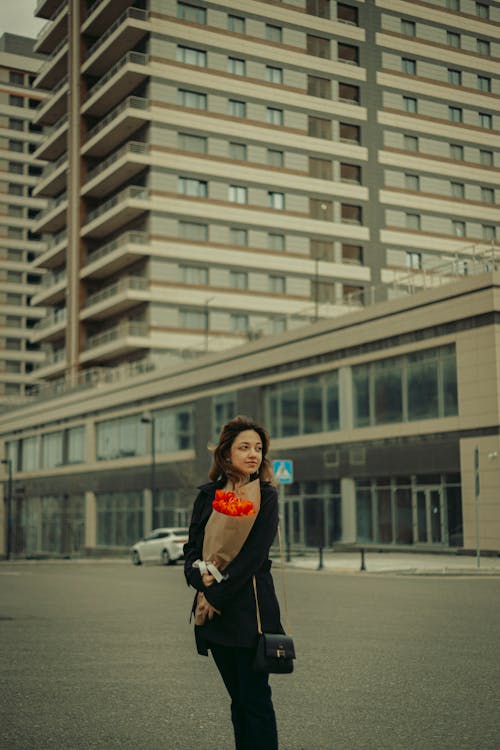 A woman holding a bouquet of flowers in front of a building