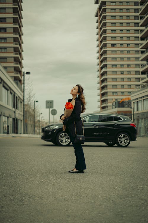 A woman standing in front of a car in a parking lot