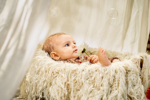 A baby is sitting in a white chair with a blanket