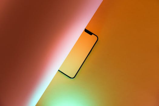 Artistic composition of a smartphone partially hidden on a vibrant yellow background, creating an abstract visual effect.