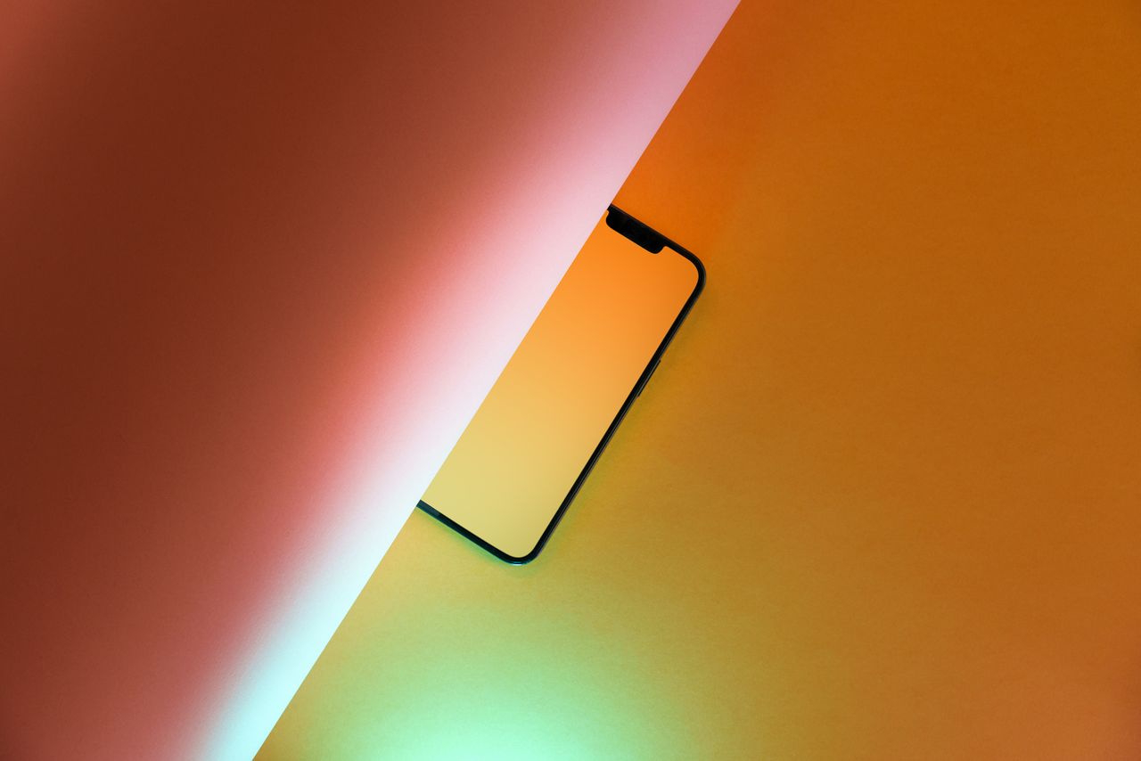 artistic composition of a smartphone partially hidden on a vibrant yel