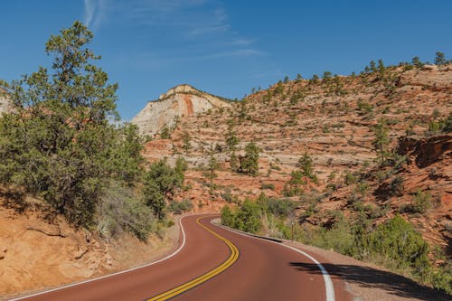 Free A winding road in the desert with a mountain in the background Stock Photo