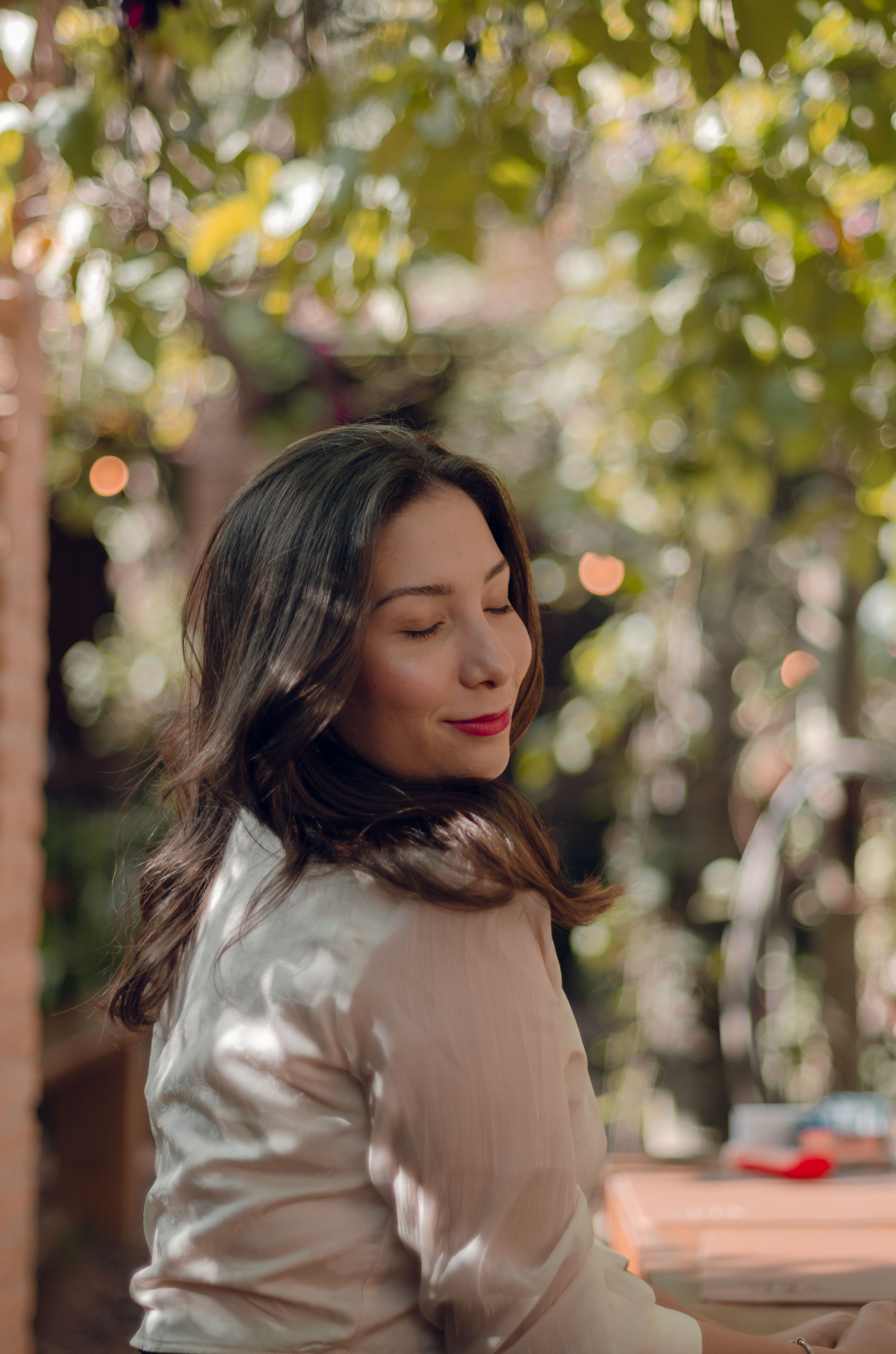 Young woman with closed eyes savoring the peaceful outdoor atmosphere under lush greenery.